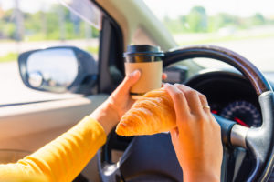 Woman Eating Food And Drinking Coffee While Driving