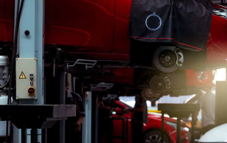 The back of a body shop with a red car lifted